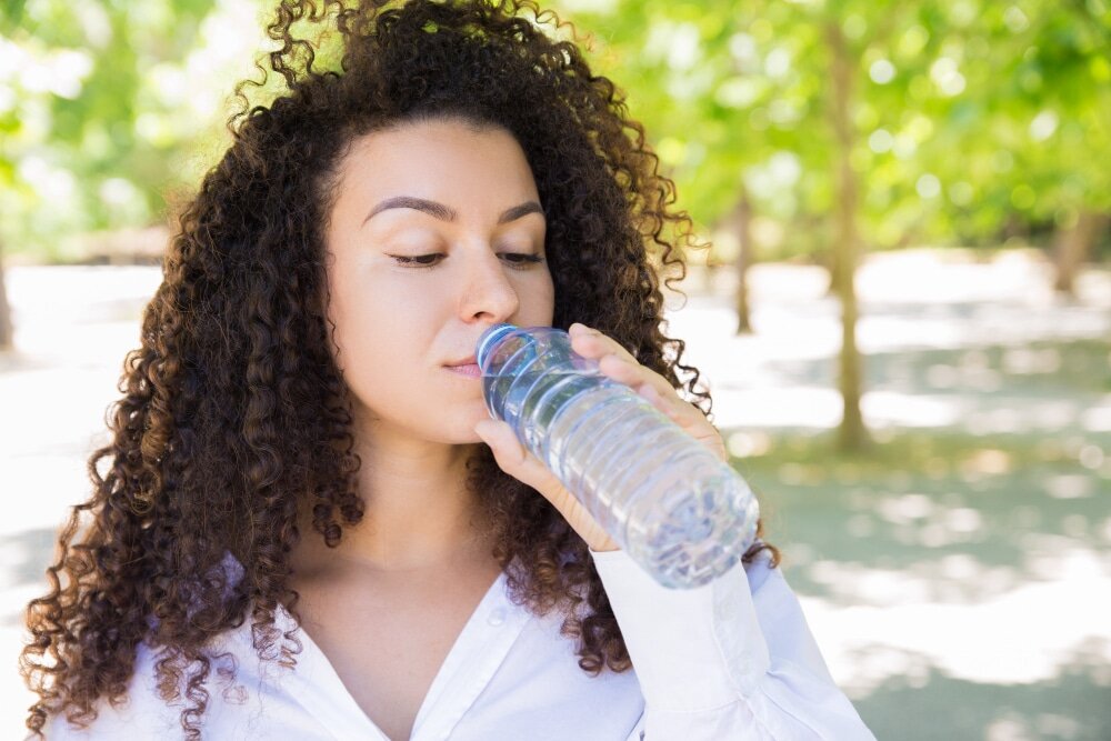 Hydratation : 5 bons réflexes Femme dehors qui boit de l'eau